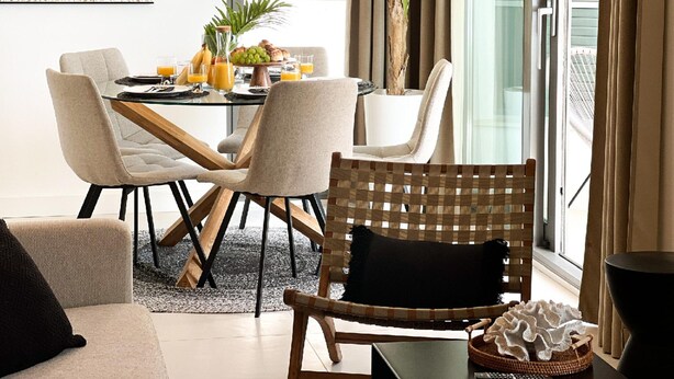 A modern dining area with a glass table, cushioned chairs, a potted plant, and a view of the city through large windows. - Omis Seaside Retreat for Family (Imotski)