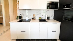 A modern kitchen with white cabinets, a black countertop, and stainless steel appliances. - Omis Seaside Retreat for Family (Imotski)