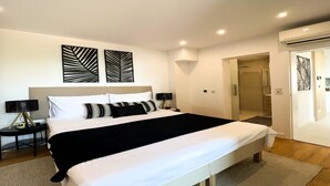 A modern bedroom with a large bed, two bedside tables, a wall-mounted lamp, and a door leading to a bathroom. - Omis Seaside Retreat for Family (Imotski)