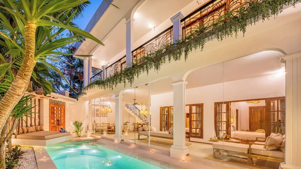 Un'area piscina di lusso con una grande piscina, zone relax e una scalinata che conduce a un livello superiore.