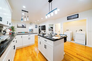 A modern kitchen with white cabinets, a black countertop, and wooden flooring. - Newly Renovated 4BR Worcester Home • Pet-Friendly • Near I-290 & Park 16-2 (Worcester)