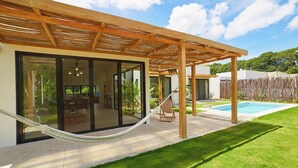 Una casa moderna con un porche cubierto, piscina y una hamaca.
