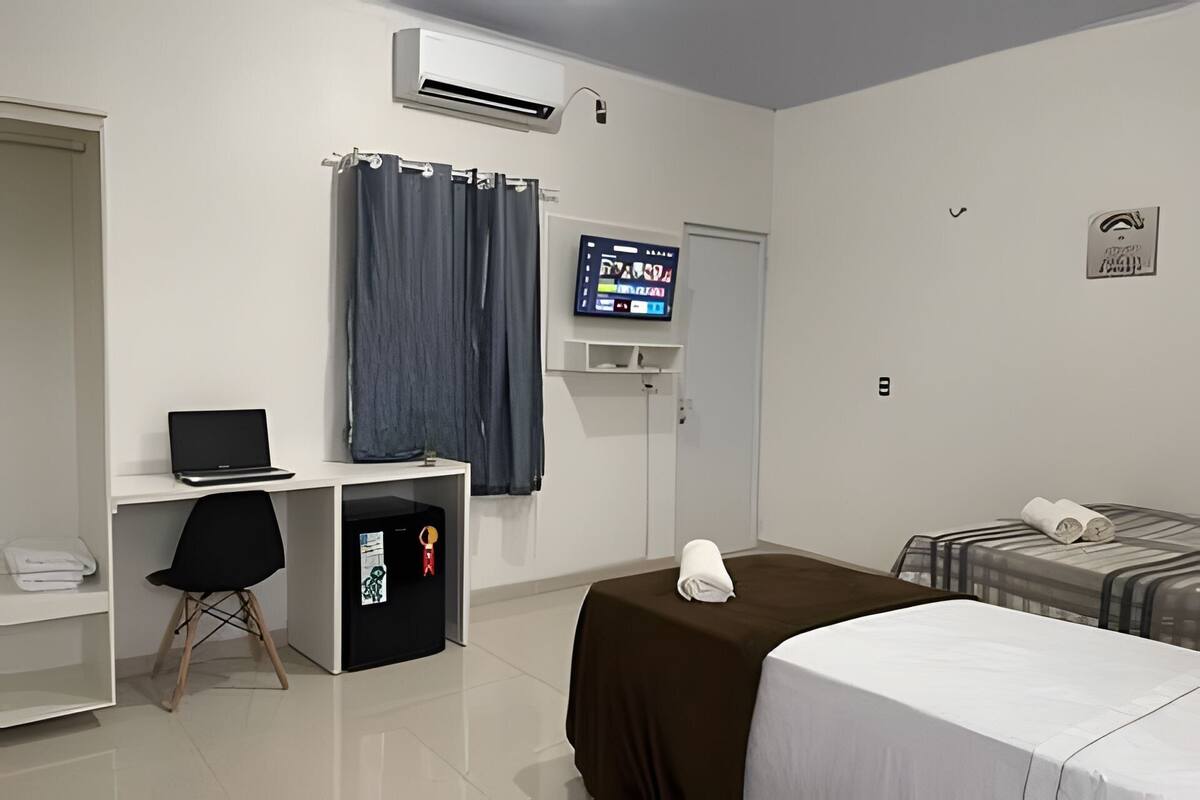 Une chambre d’hôtel comprenant un lit, un bureau avec un ordinateur portable, une télévision et un petit placard.