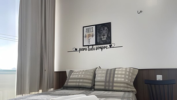 A modern bedroom with a large bed, a view of the sea, and a motivational quote on the wall. - Apartamentos Vitória (Barreirinhas)