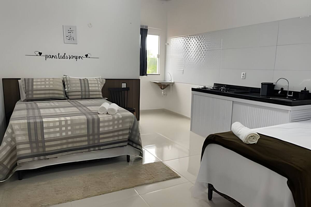Une chambre d’hôtel avec un lit, un petit bureau, un lavabo et une fenêtre.