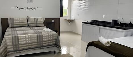 A hotel room with a bed, a small desk, a sink, and a window.
