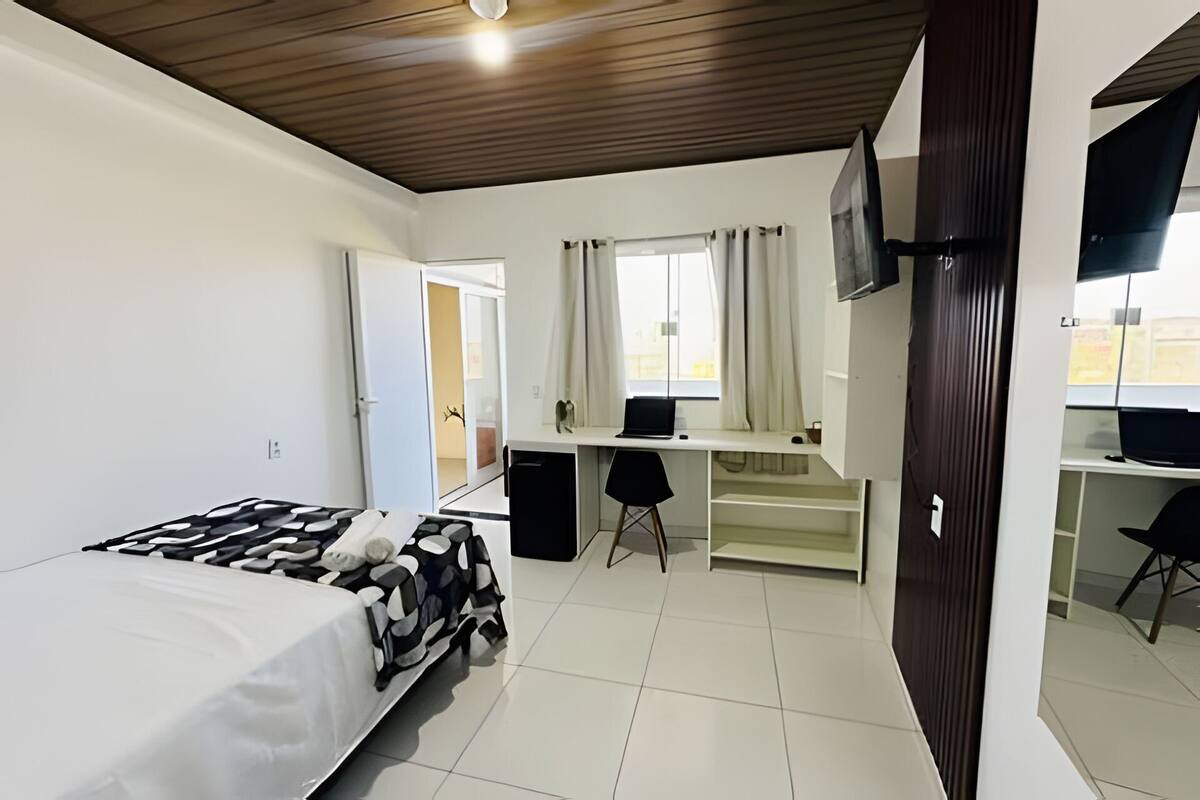 Une chambre à coucher avec un lit, un bureau, une chaise et un téléviseur.