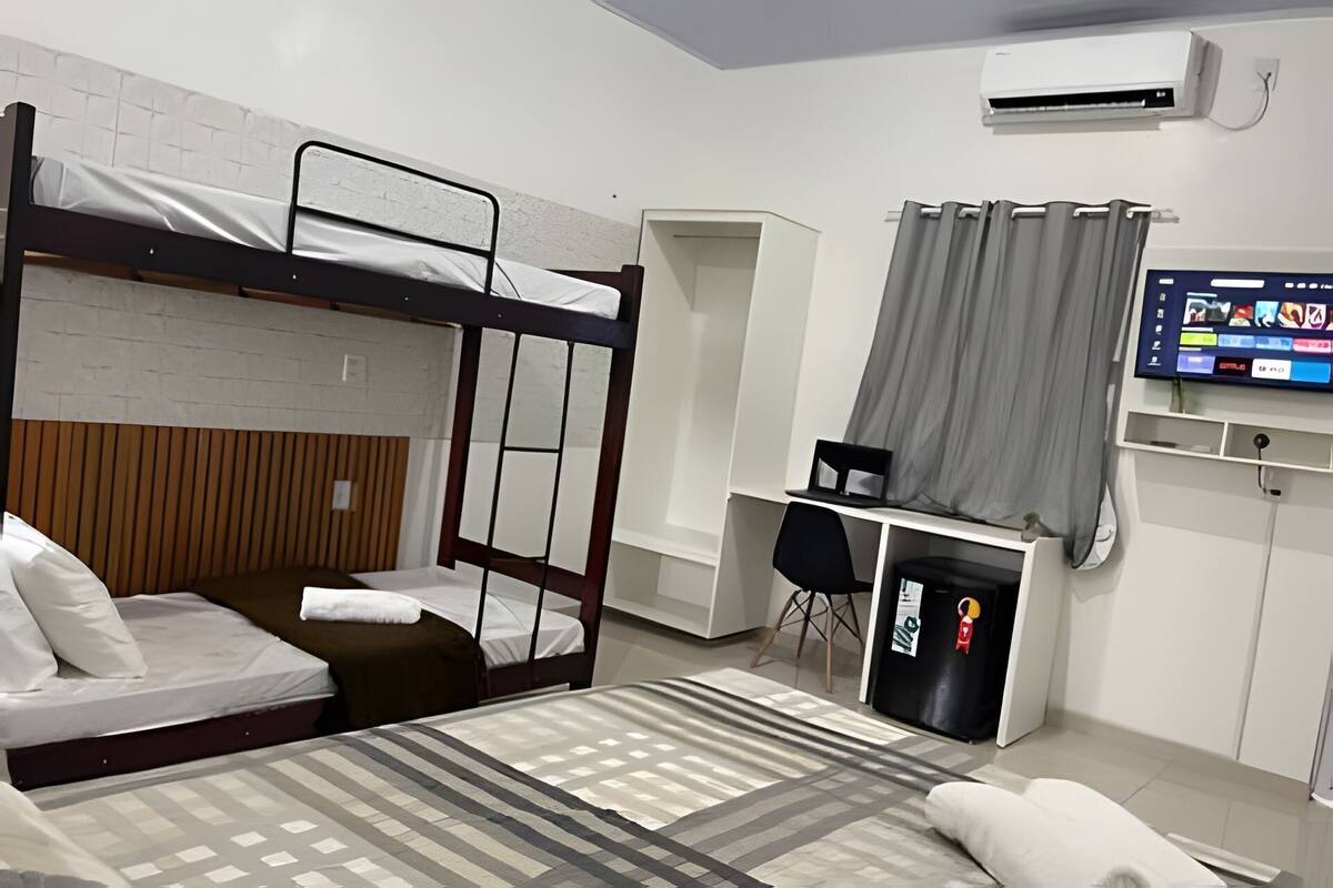 Une chambre de type dortoir, avec des lits superposés, un bureau, une chaise, un téléviseur et une armoire.