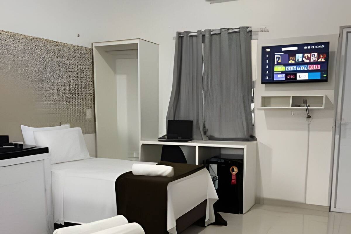 Une chambre d’hôtel moderne équipée d’un lit, d’un bureau, d’une télévision et d’un appareil de climatisation.