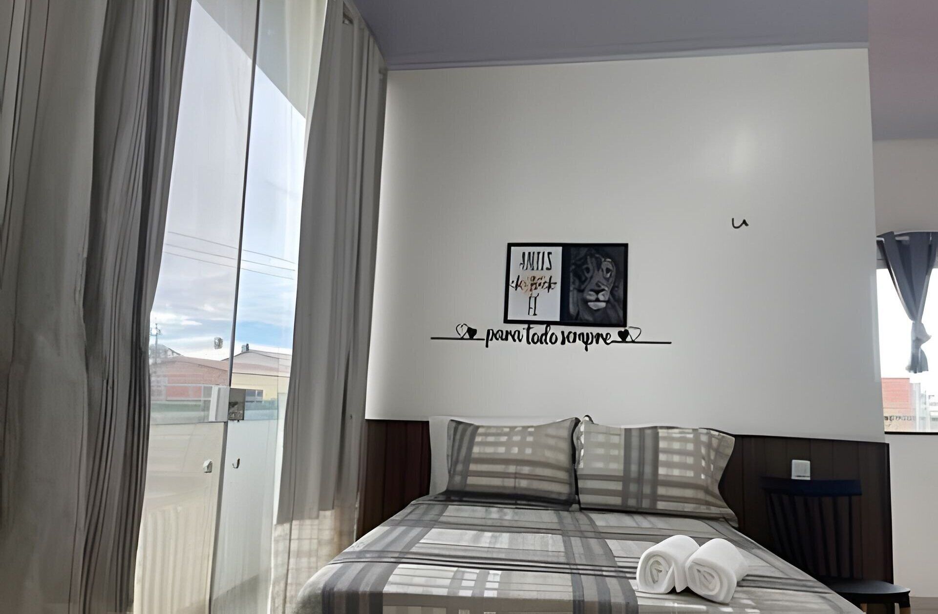 Une chambre d’hôtel moderne avec un grand lit, une vue par la fenêtre et une œuvre d’art murale.