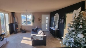Un salon chaleureux avec une cheminée, un canapé, un sapin de Noël et un téléviseur.