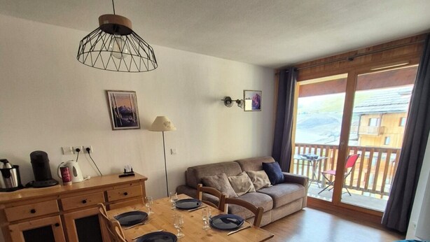 Zona pranzo con tavolo e sedie in legno, un divano e un balcone con vista.