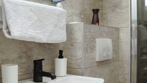 Een badkamer met een wit wastafelblad, een zwarte kraan en een handdoek aan een rek.