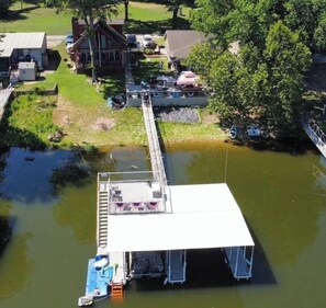 A dock extending into a body of water with a covered area and a small boat docked at the end.