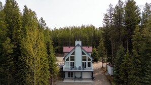 Een huis met twee verdiepingen en een balkon, omgeven door een dicht bos.