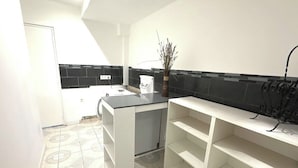 A kitchen with white cabinets, a black countertop, and a tiled backsplash.