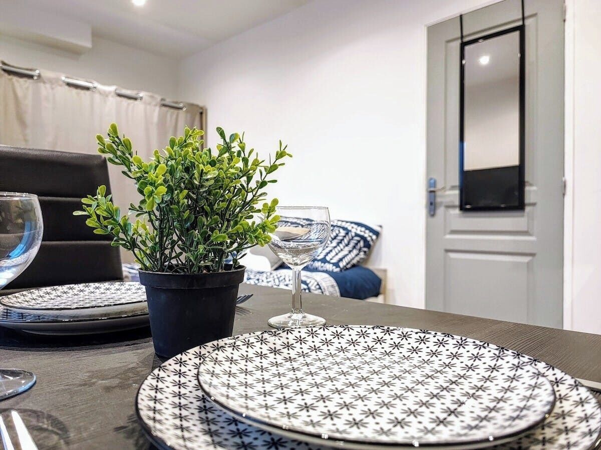 Une table à manger avec des assiettes, un verre et une plante en pot dans une chambre d’hôtel.