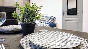 A dining table with plates, a glass, and a potted plant in a hotel room.