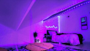 Un dormitorio con una cama, una mesita pequeña y una lámpara de pared.