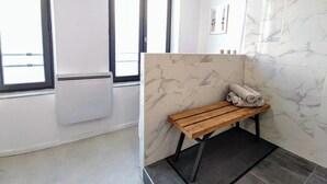 Un baño con un banco, un perchero y una ventana.