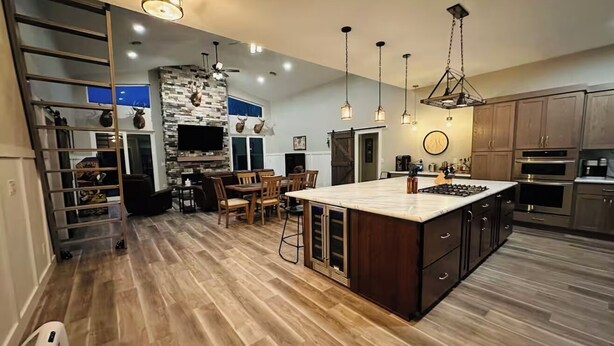 A modern kitchen with a central island, wooden flooring, and built-in appliances. - Finger Lake Retreat (Prattsburgh)