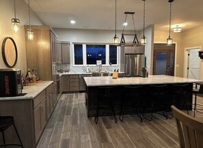 A modern kitchen with a large island, wooden cabinets, and pendant lighting. - Finger Lake Retreat (Prattsburgh)
