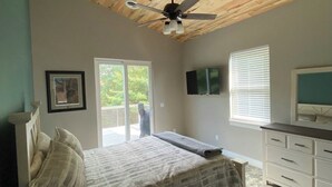 A bedroom with a bed, a ceiling fan, a dresser, and a TV. - Finger Lake Retreat (Prattsburgh)