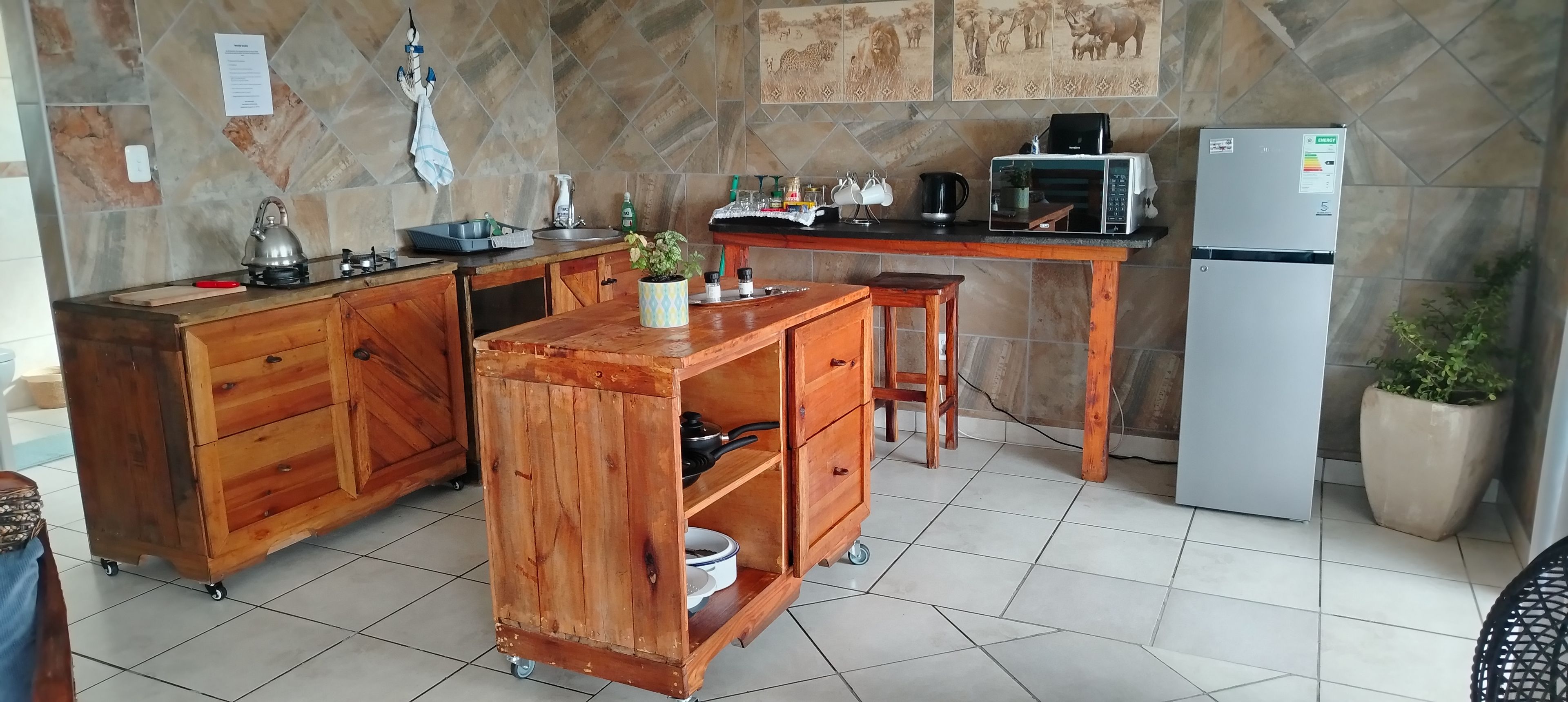 Une cuisine avec un îlot central en bois, un réfrigérateur et un dosseret carrelé.