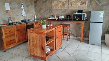 Une cuisine avec un îlot central en bois, un réfrigérateur et un dosseret carrelé.