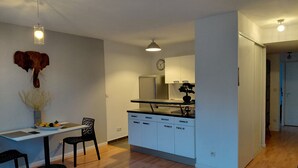 Uma cozinha moderna com armários brancos, uma área de jantar com mesa e cadeiras, e uma cabeça de elefante decorativa na parede.