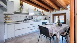 Una cucina con mobili bianchi, un fornello a gas e un tavolo da pranzo per due persone.