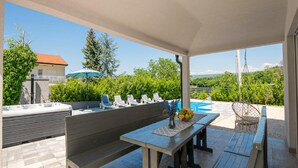 An outdoor patio with a wooden table, benches, and a hot tub. - Paradise Villa in the Countryside (Imotski)