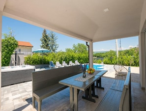 An outdoor patio with a wooden table, benches, and a hot tub. - Paradise Villa in the Countryside (Imotski)