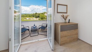 A balcony with a table and chairs, a wooden cabinet, and a framed picture on the wall. - Paradise Villa in the Countryside (Imotski)