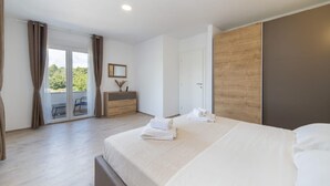 A hotel room with a large bed, a wooden wardrobe, a desk with a chair, and a sliding glass door leading to an outdoor area. - Paradise Villa in the Countryside (Imotski)