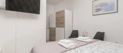 Une chambre à coucher moderne avec un lit, une télévision, un tableau et un miroir.