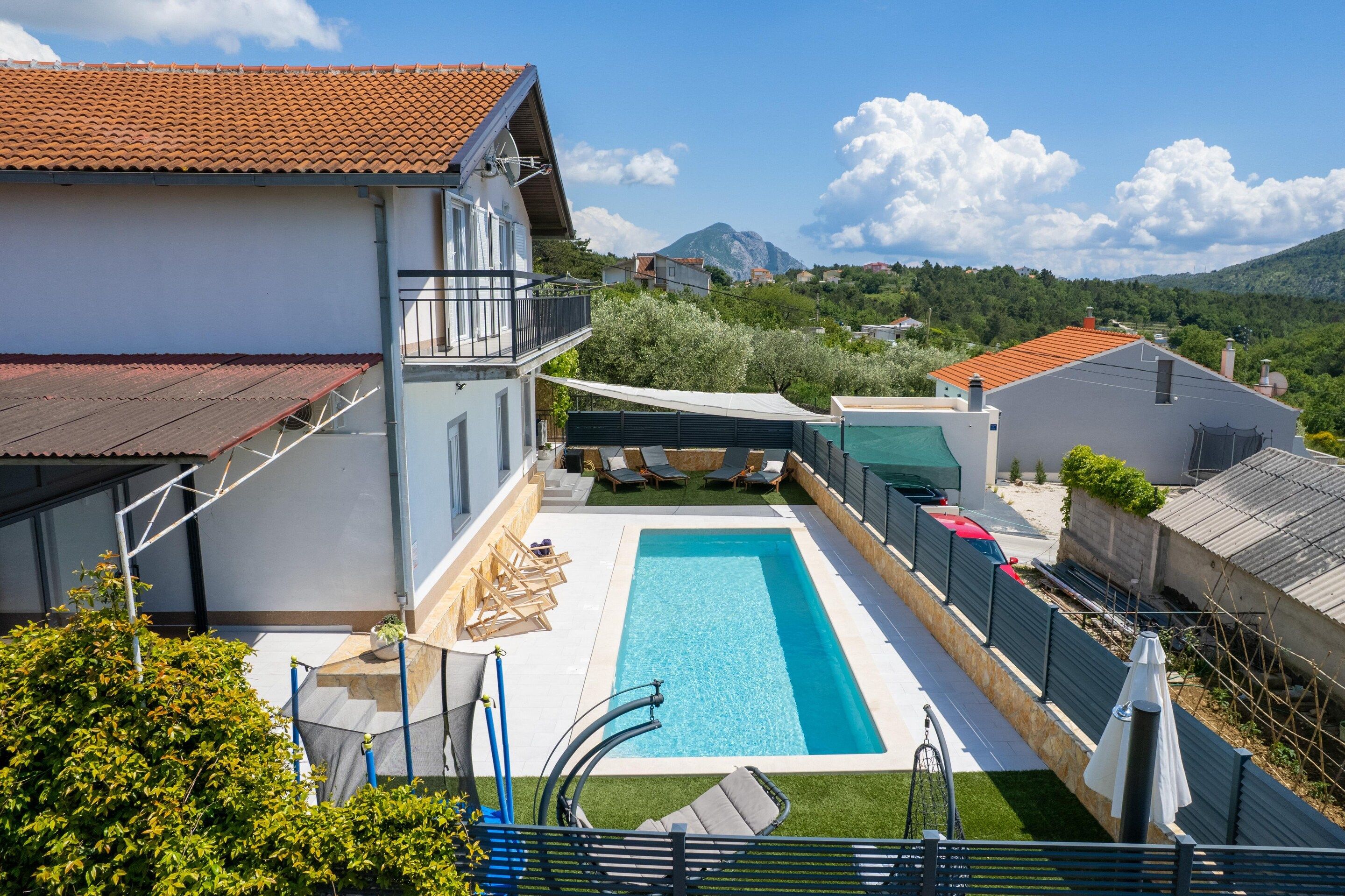 A residential property with a swimming pool, a covered patio, and a view of a mountain.