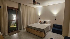 A bedroom with a bed, a ceiling fan, a nightstand, a chair, and a window with curtains.