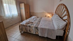 A bedroom with a wooden bed, a wardrobe, a window with curtains, and a tiled floor. - Vacation home with pool and within walking distance to the sea (Pachino)