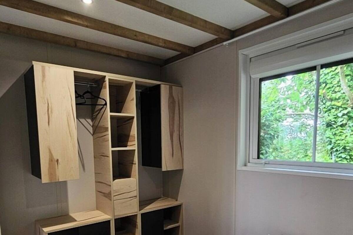 Un dormitorio con cama, armario de madera y ventana con vistas a zonas verdes.