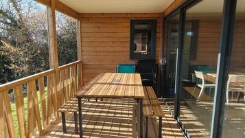 A wooden deck with a table and chairs, a sliding glass door, and a view of the outdoors.