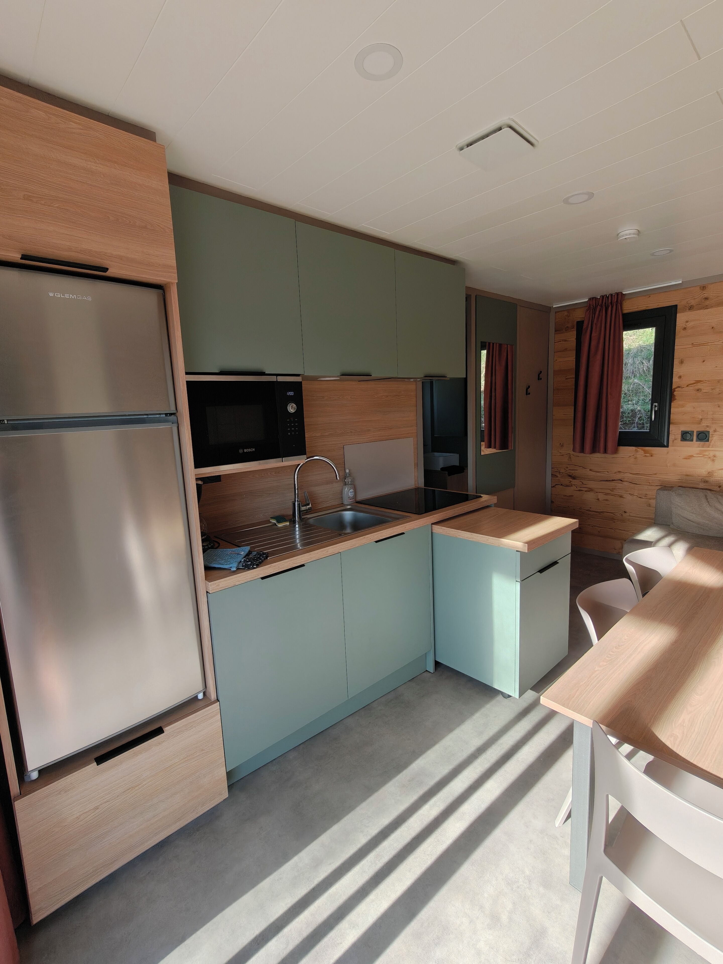 Una cocina compacta equipada con refrigerador, microondas, pileta y comedor con mesa y sillas.