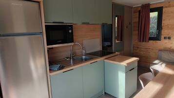 Una cocina compacta equipada con refrigerador, microondas, pileta y comedor con mesa y sillas.