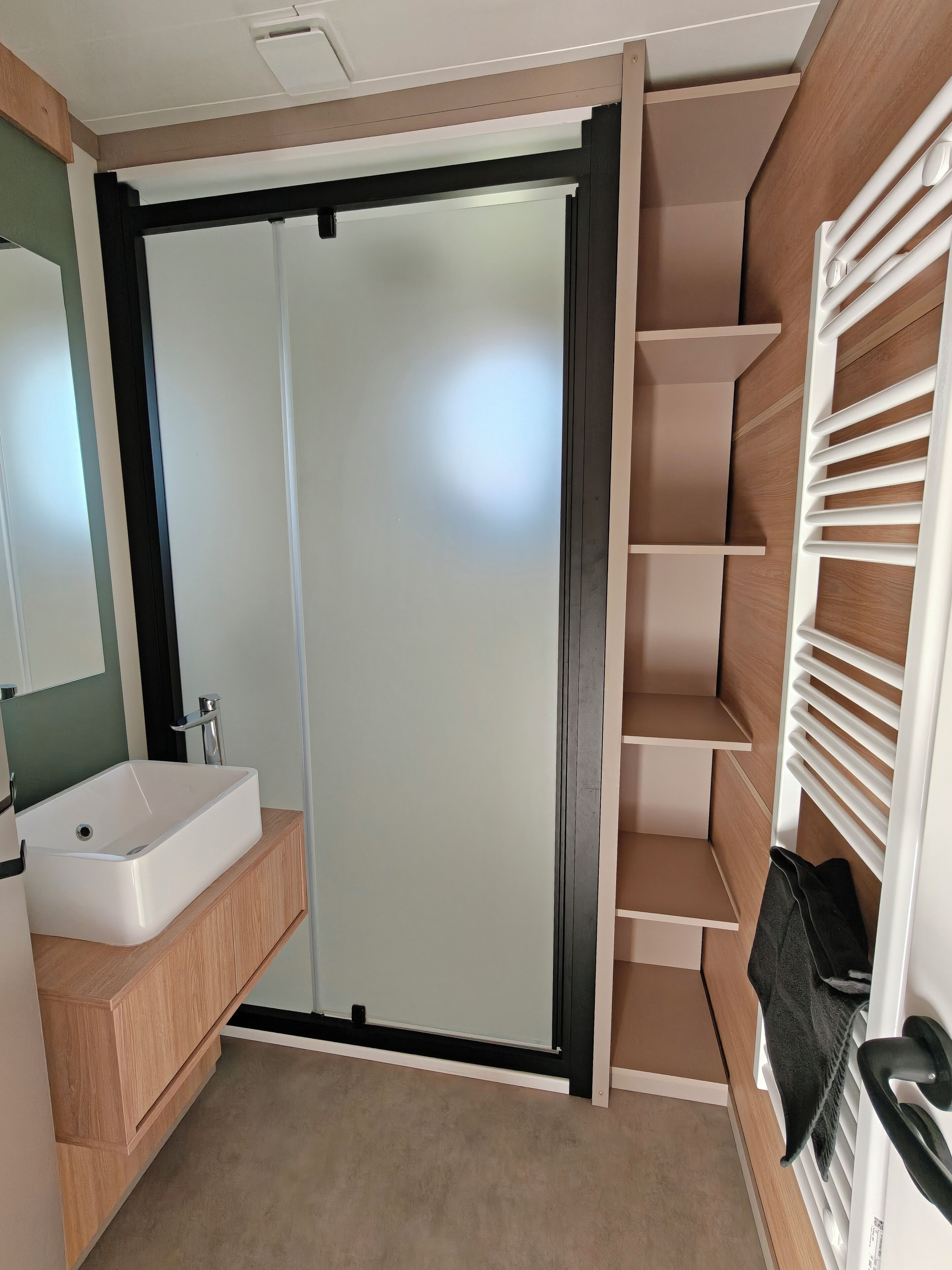 Une salle de bain moderne dotée d’un lavabo intégré, d’un miroir et d’une cabine de douche.