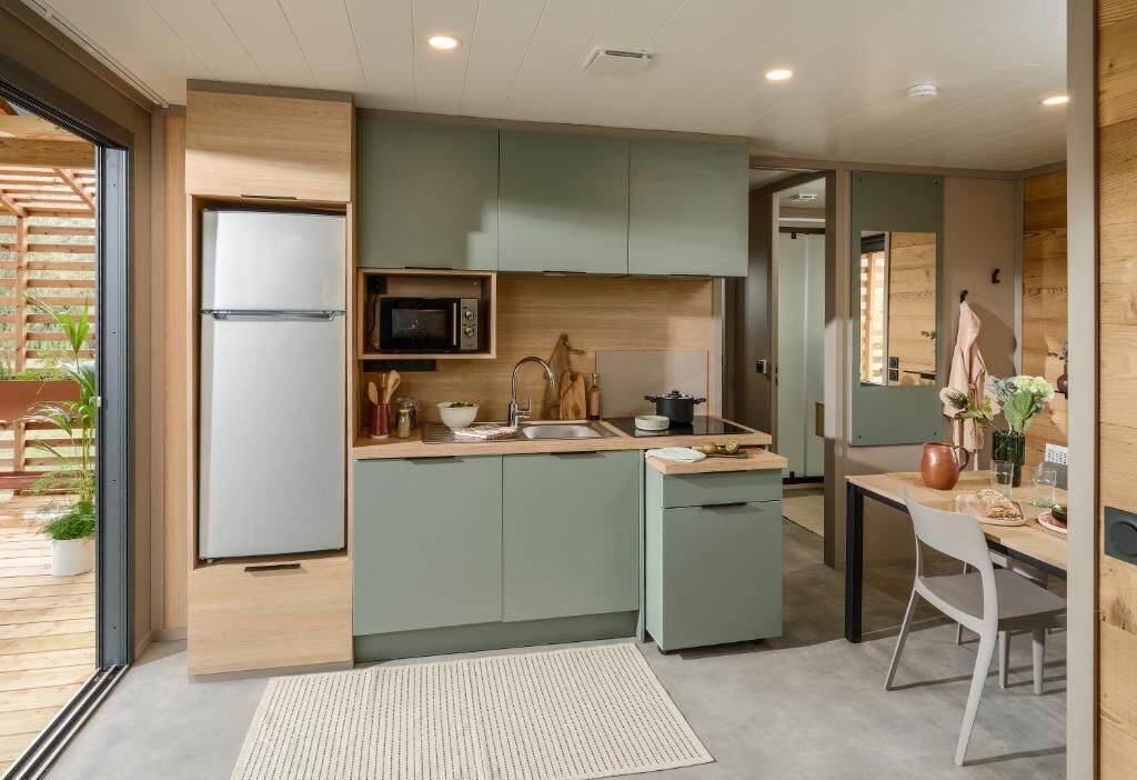 A compact kitchen with a built-in microwave, a sink, and a small dining area with a table and chairs.