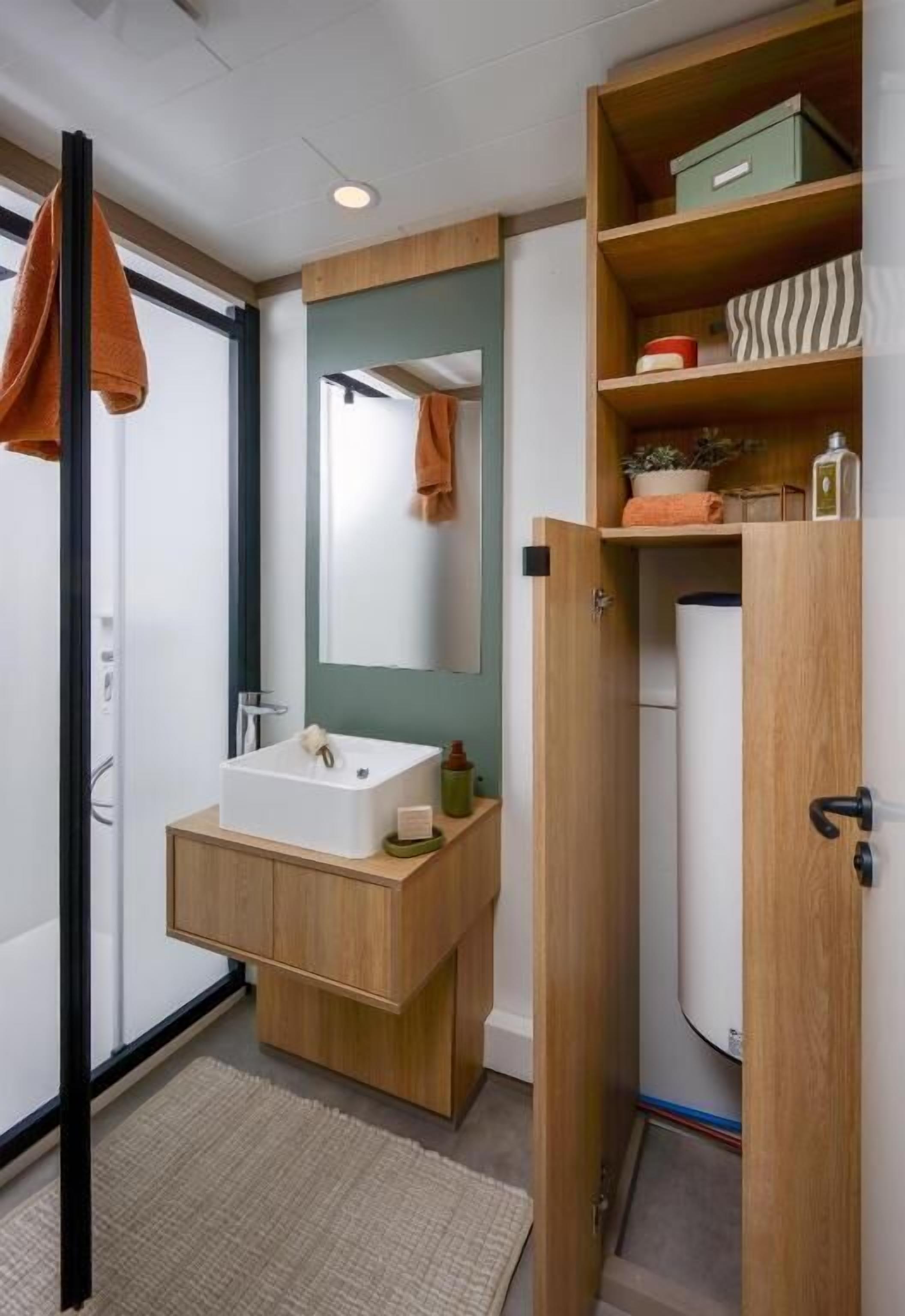 Une salle de bain moderne avec un meuble-lavabo en bois, un lavabo blanc, un miroir et un porte-serviettes.