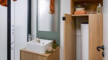 Une salle de bain moderne avec un meuble-lavabo en bois, un lavabo blanc, un miroir et un porte-serviettes.