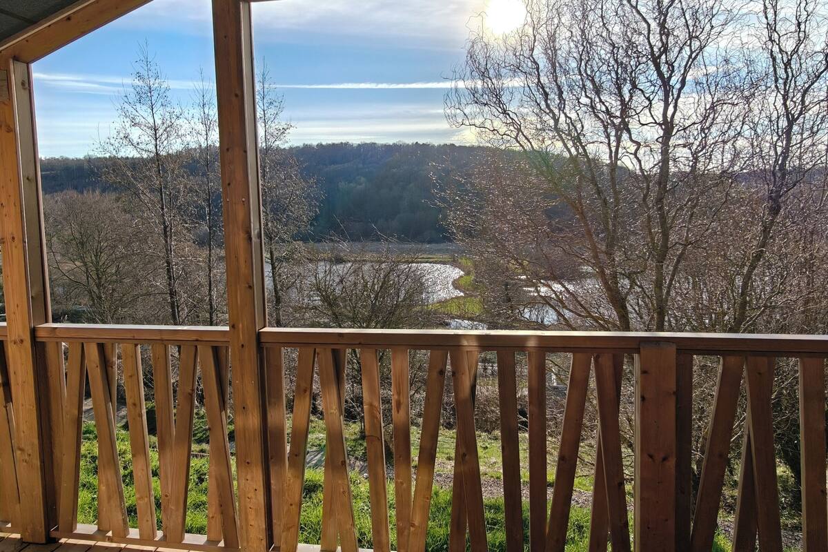 Una terraza de madera con vistas a un bosque y un río.