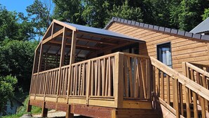 A wooden deck with a glass enclosure, a staircase, and a building with a sloped roof.