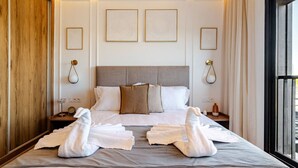 Ein Hotelzimmer mit einem großen Bett, zwei Nachttischen, einer Kopfteil und gerahmten Kunstwerken an den Wänden.